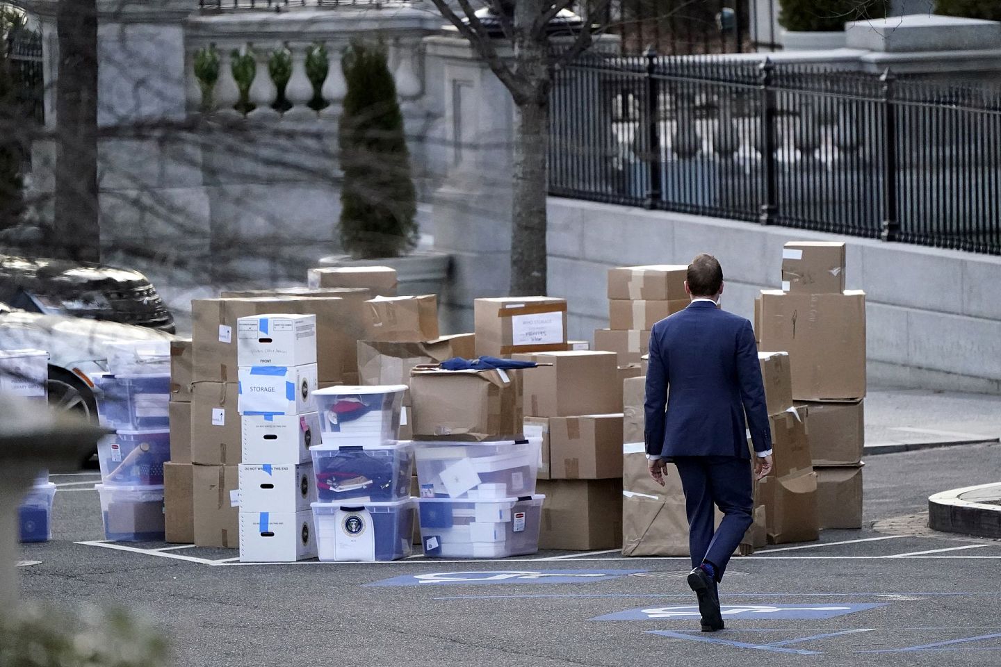 2021年1月14日，一名男子从白宫大楼西翼外的艾森豪威尔行政办公楼搬出来的大堆箱子旁走过。（AP）