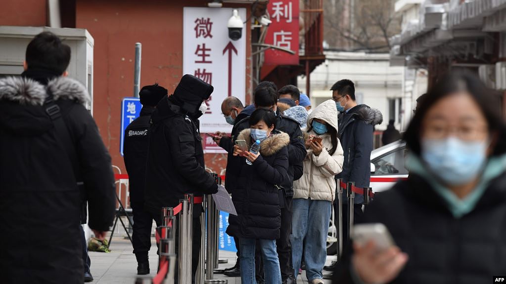 2021年1月14日人们在北京一家医院排队测试新冠病毒时通过手机刷健康码。（法新社提供）