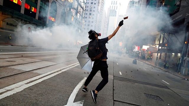 An anti-government protester reacts as police fire tear gas during a march billed as a global 