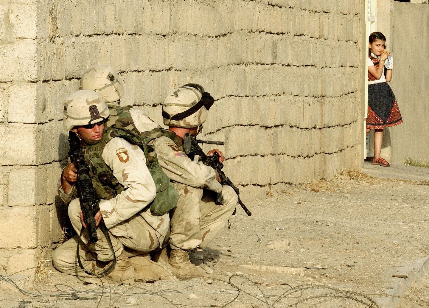 2003年，以美军为首的军队进攻伊拉克，推翻时任总统萨达姆的政府。图为2003年7月，伊拉克城市摩苏尔（Mosul），一名当地女童注视出现在家门口的美军。（Getty Images）