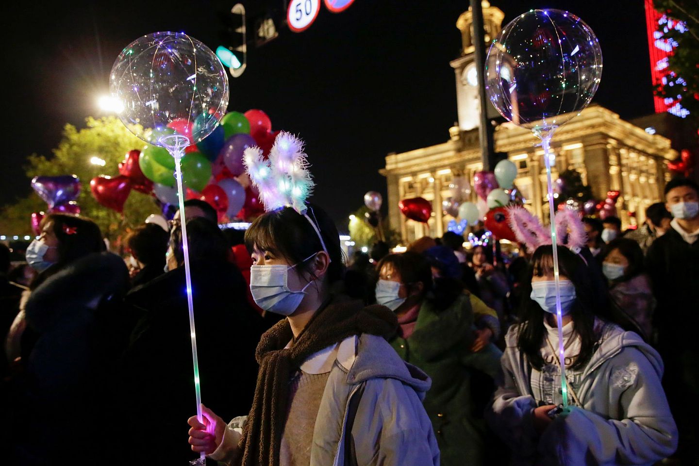 2020年12月31日，在曾经的疫情爆发中心，中国武汉民众聚集在一起，迎接新年的到来。一些女孩拿着漂亮的发光气球。（Reuters）