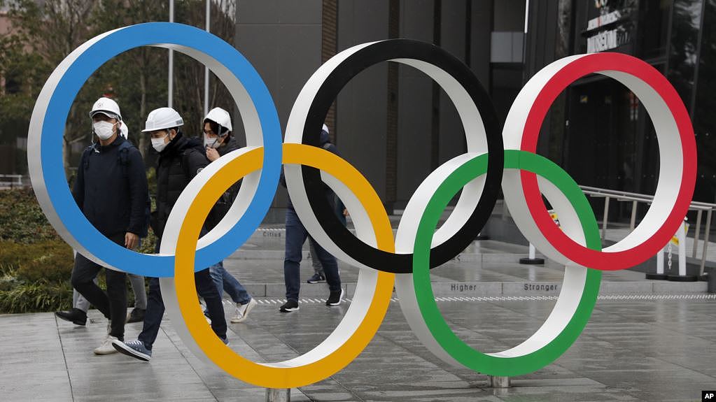资料照：戴着口罩的东京市民走过街头的奥运标识。（2020年3月4日）