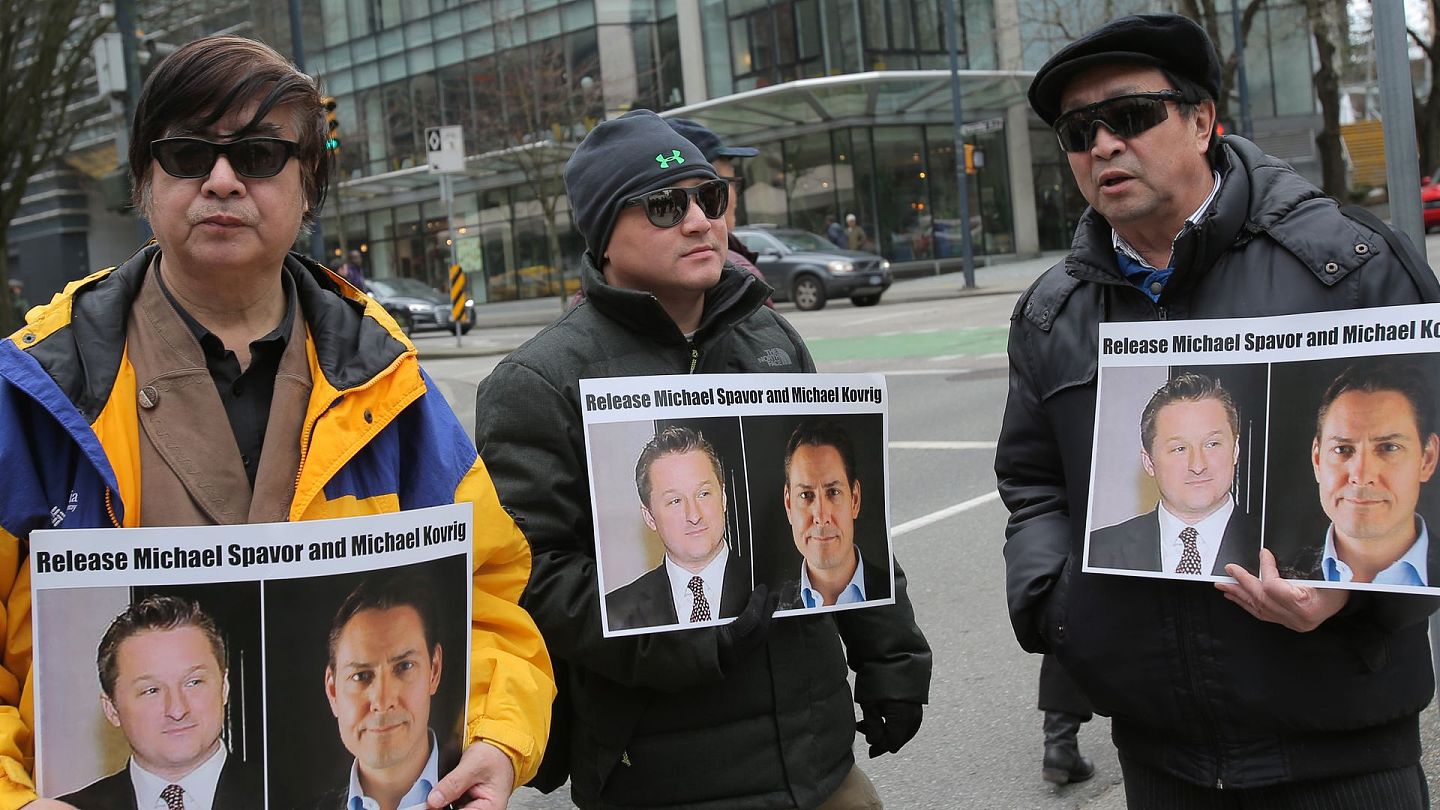 康明凯被捕：图为2019年3月6日，温哥华示威者手持加拿大前外交官康明凯及公民斯帕弗的照片，在卑诗省高等法院外要求中方释放他们。（Getty）