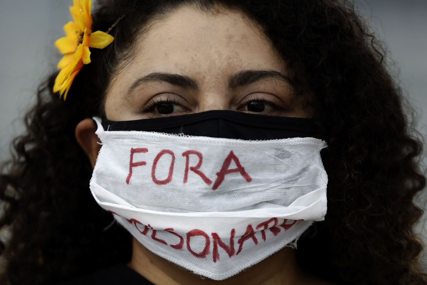 1月17日，在巴西巴西利亚总统府外，一名示威者戴着一个用葡萄牙语写着“博尔索纳罗下台”的口罩，抗议博尔索纳罗的疫情应对行动差强人意。（AP）