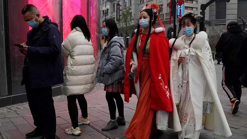 2021年1月23日，星期六，身着传统服装，戴着口罩的妇女出现在武汉市一条受欢迎的购物街。