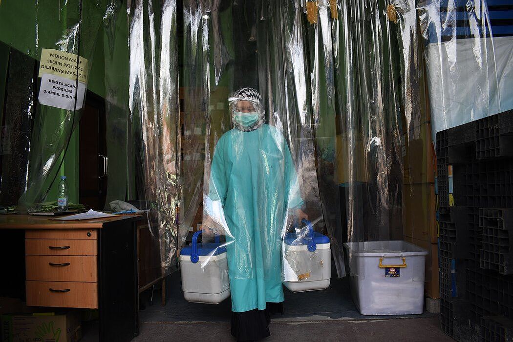 印度尼西亚的一名卫生工作者运送装有科兴疫苗的集装箱。当地官员最初曾说，科兴疫苗的有效率为68%。