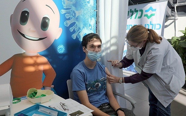  1月23日，在以色列中部城市特拉维夫的一处卫生服务站内，一名男孩接种新冠疫苗。