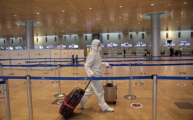 1月19日，穿戴防护装备的旅客走在以色列本古里安国际机场。