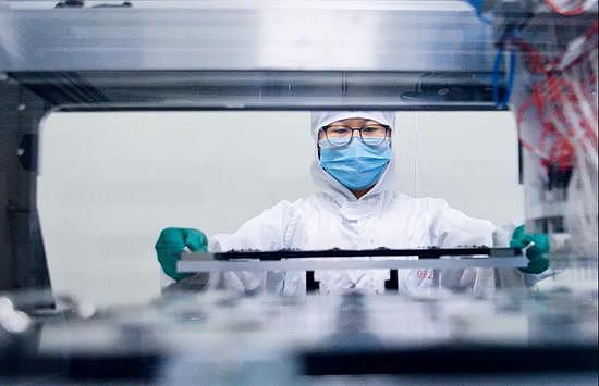  四川成都的一家生物公司内，洁净车间工作人员将可检测新冠病毒的核酸检测试剂盒芯片送进印制机器。图/中新