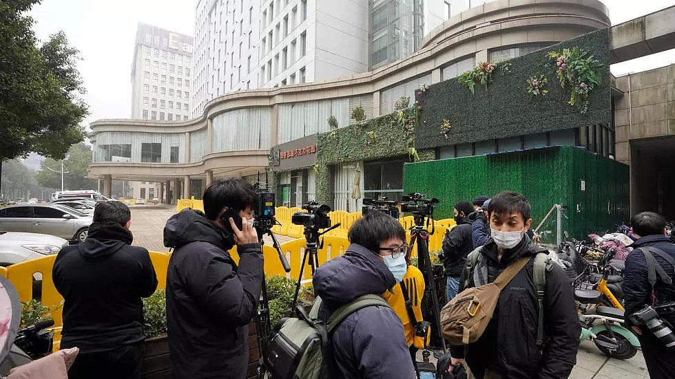 1月28日武汉一酒店门前等待世卫调查专家结束隔离乘车离开的记者们。