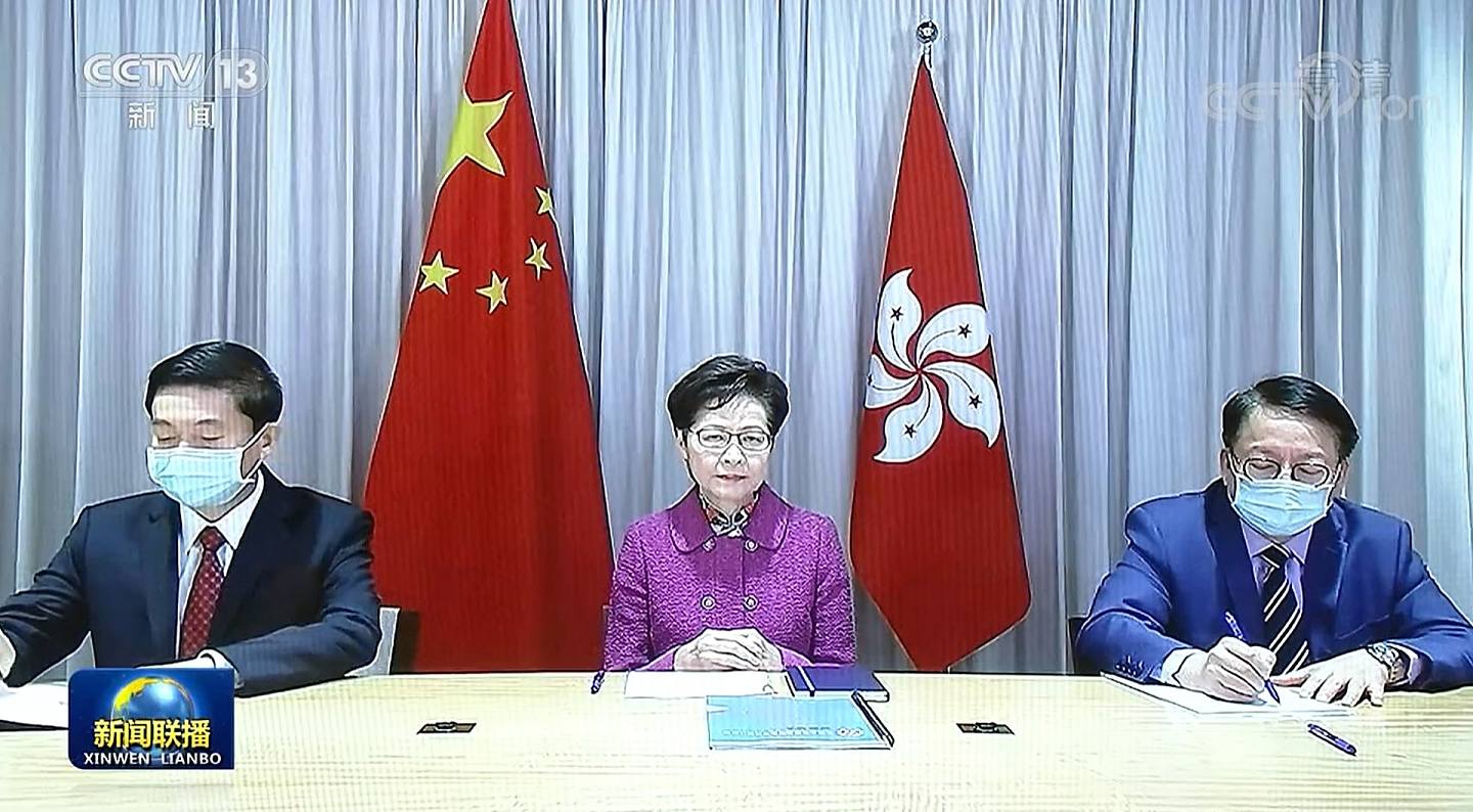 林鄭月娥1月27日在香港透過視像向習近平述職，坐在兩旁分別是中聯辦主任駱惠寧（左）、特首辦主任陳國基。（新聞聯播截圖）