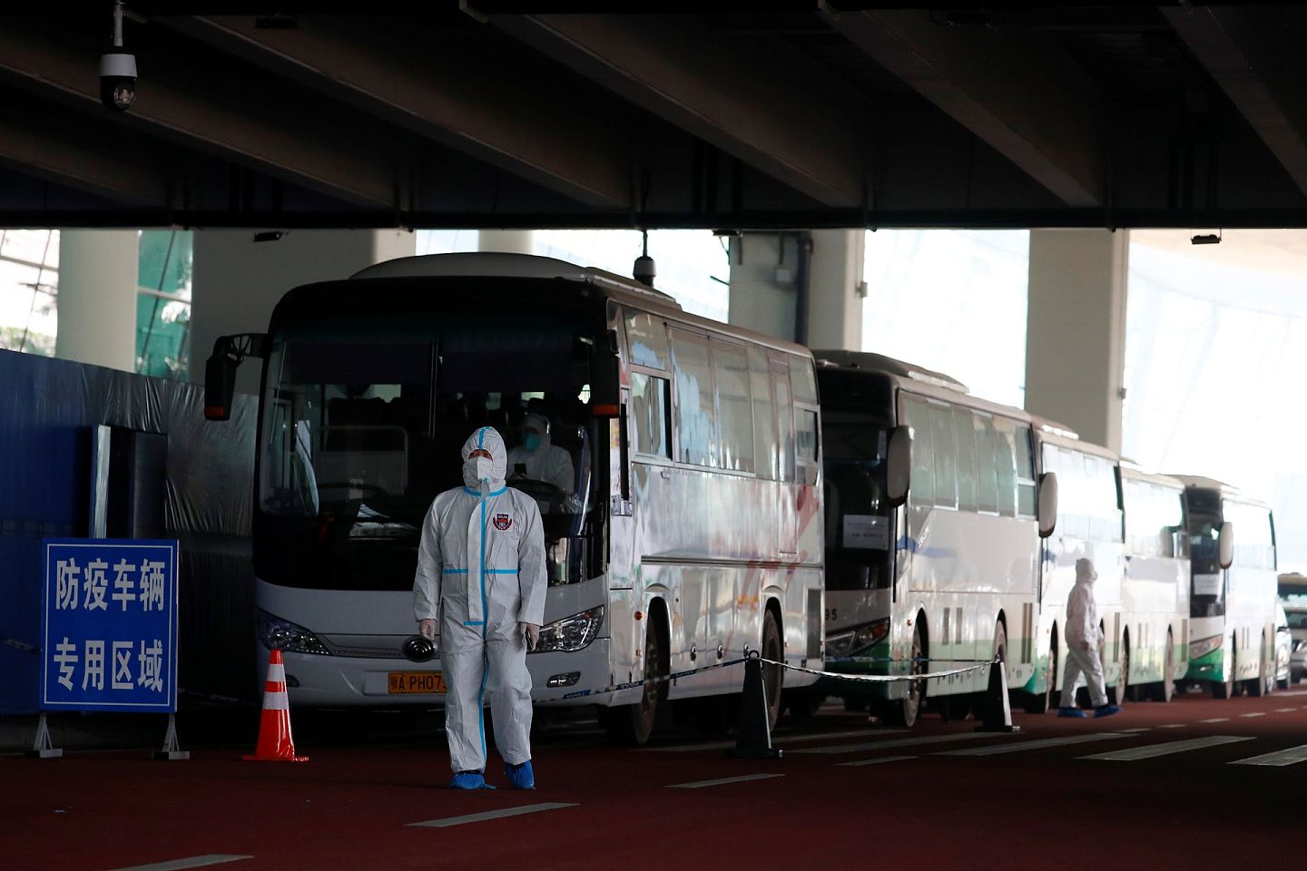2020年1月14日，世界卫生组织负责调查新冠肺炎起源的小组在抵达武汉前，一名身穿防护服的工作人员站在公共汽车旁边。（Reuters）