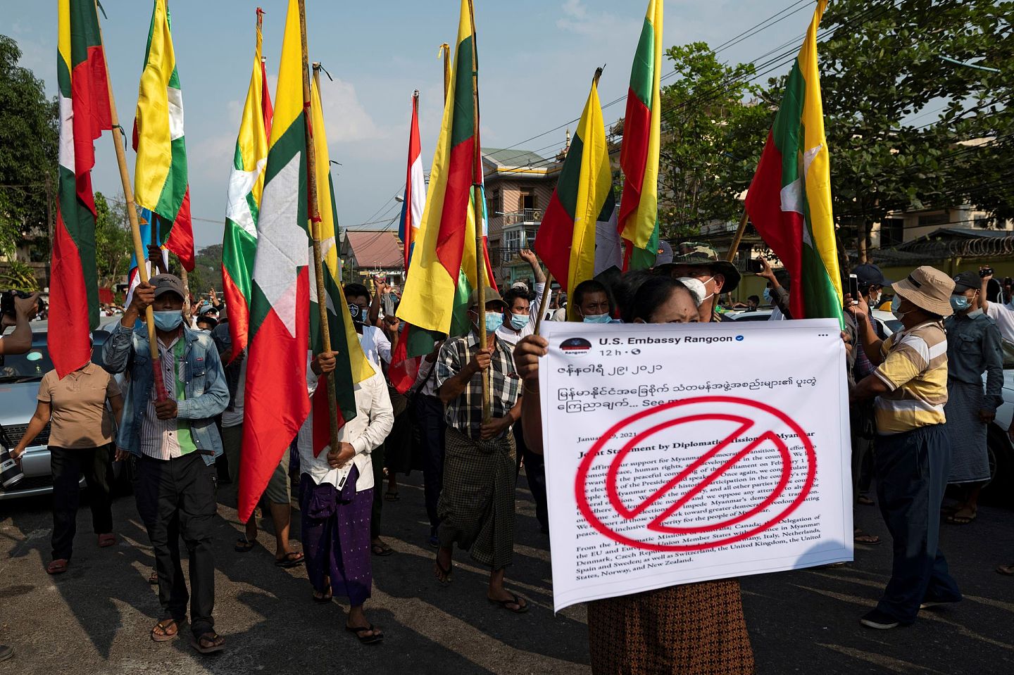 缅甸民众高举旗帜，在街头游行。（Reuters）