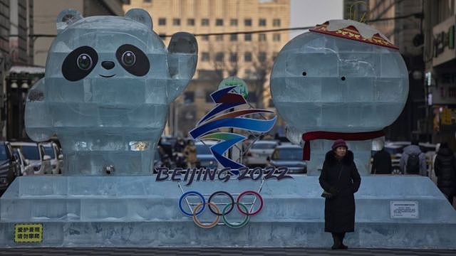 A woman stands next to an ice advertisement for the Beijing 2022 Olympics in Harbin, Heilongjiang province, China, 11 January 2021