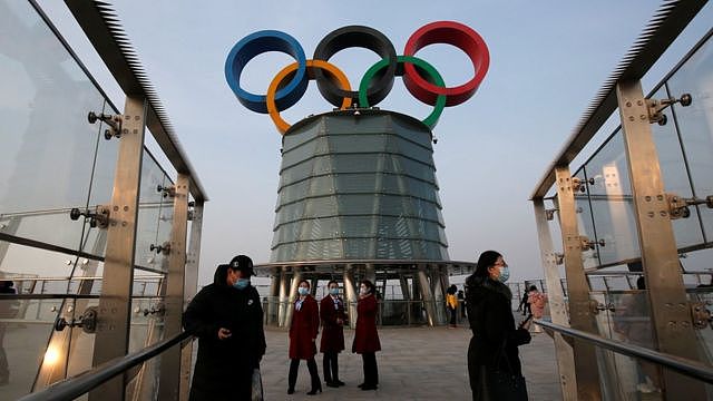 People wearing face masks following the coronavirus disease (COVDI-19) outbreak are seen near a giant Olympic symbols at the Olympic Tower, during an organised media tour to 2022 Winter Olympic Games venues in Beijing, China January 22, 2021.