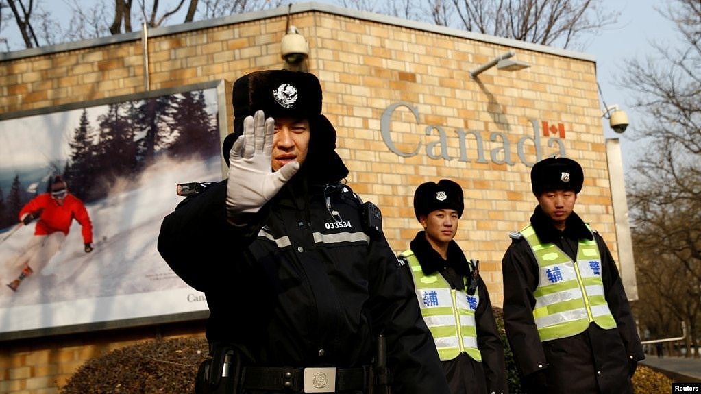 在加拿大驻北京大使馆外的一名中国警察向摄影记者打出禁止的手势。（2018年12月20日）