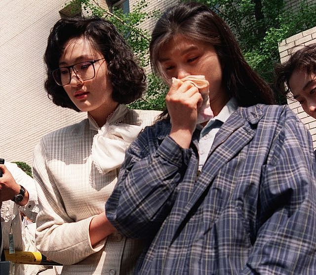 Kim Hyun-hui holds a handkerchief to her nose as she is led from a courtroom in Seoul by a woman investigator, on 25 April 1989