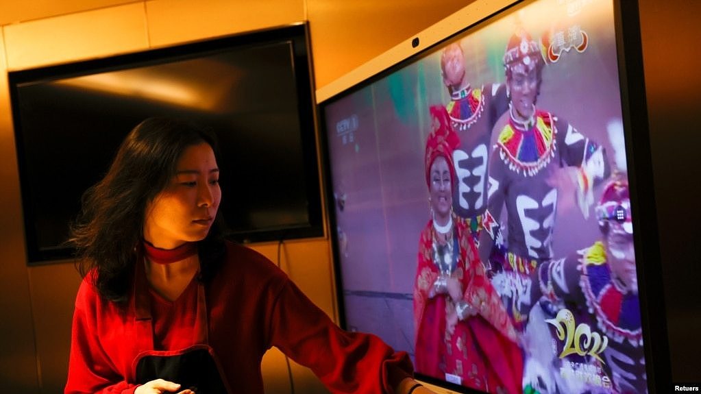 一名女子在北京一家海底捞餐厅和家人吃年夜饭时观看央视春节晚会。（2021年2月11日）