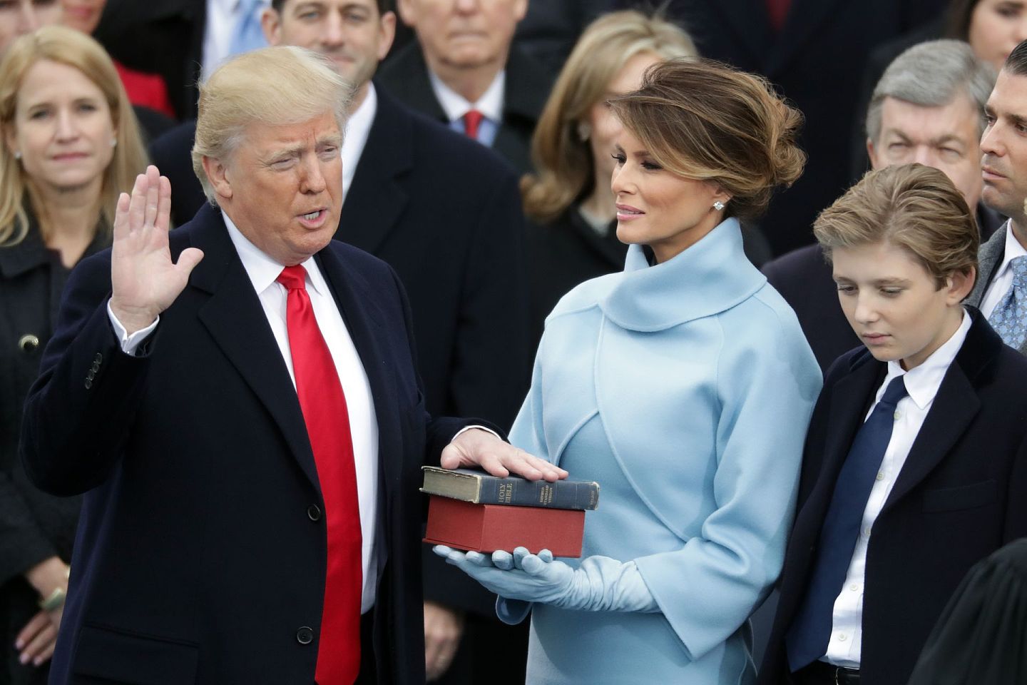 2017年1月20日，特朗普于华盛顿宣誓就任美国总统，夫人梅拉尼娅手捧圣经。梅拉尼娅穿的Ralph Lauren的粉蓝礼服，让人联想起积琪莲（Jacqueline Kennedy）首次以第一夫人名衔现身就职典礼的打扮。（Getty）