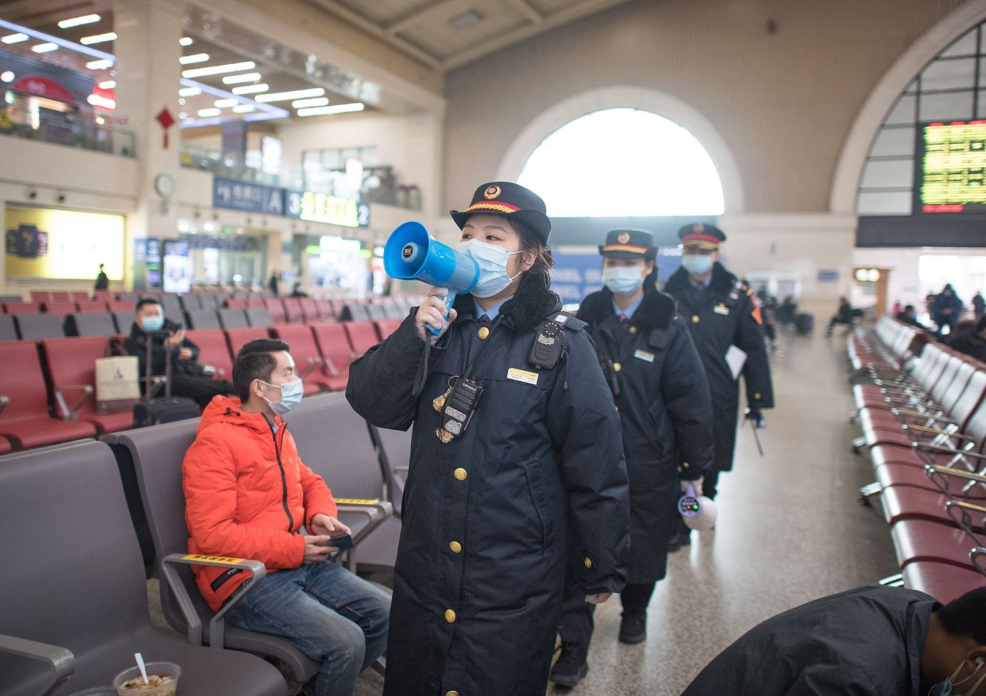 1月28日，武汉汉口火车站的工作人员在候车厅宣讲乘车防疫事项。（新华社）