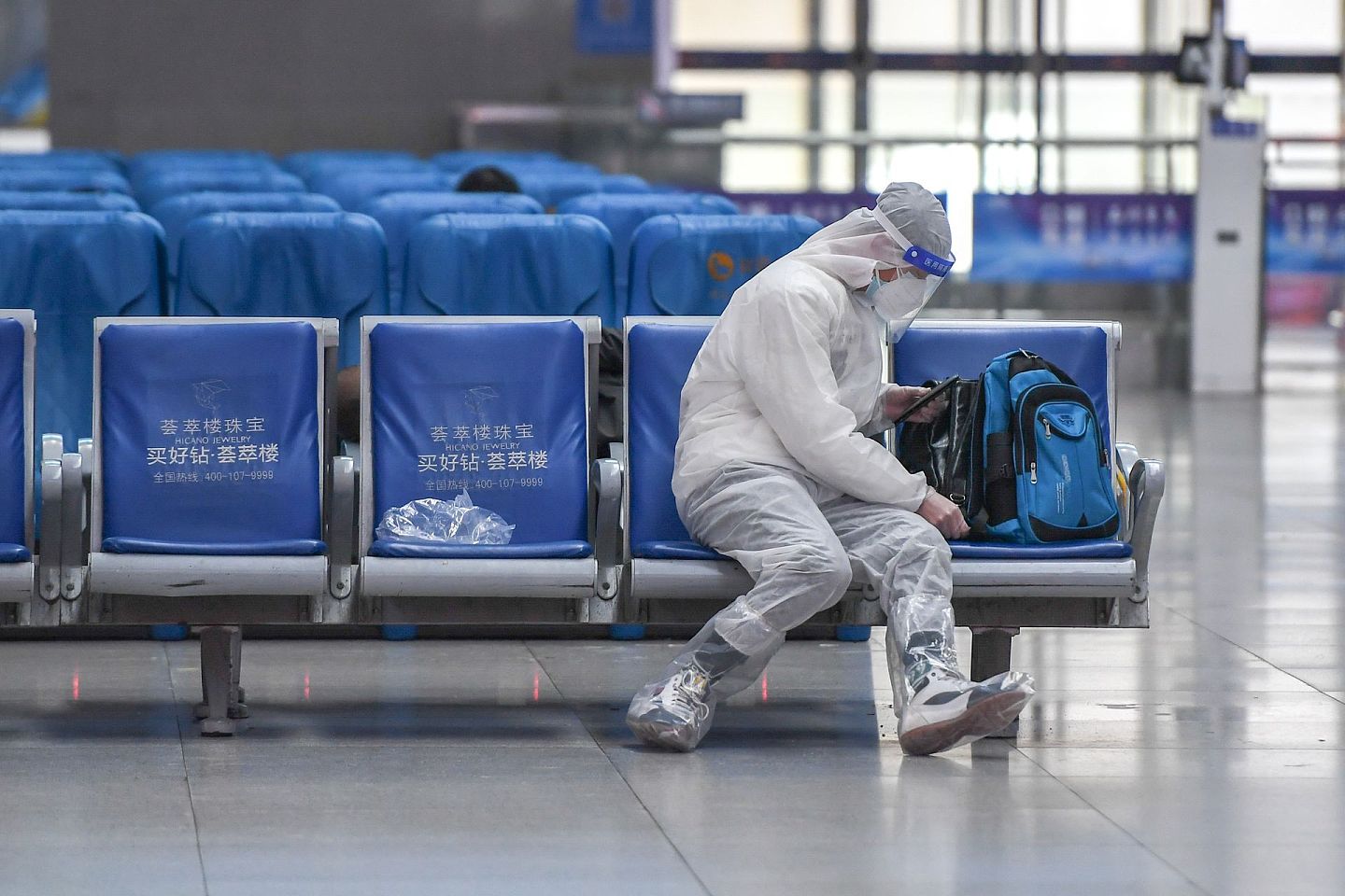 1月28日，一名旅客穿着防护服在长春站候车大厅候车。（新华社）