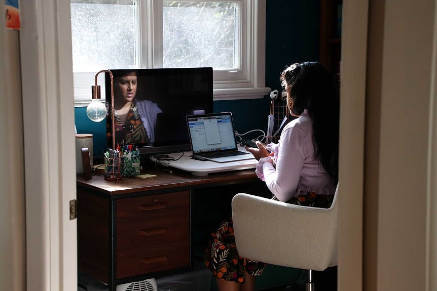 A woman at a home office looking at her phone 