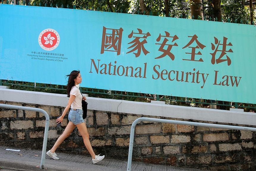 A woman walks past a promotional banner of the national security law for Hong Kong