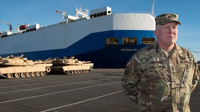 Timothy McGuire, Major General and Deputy Commanding General United States Army Europe, stands in front of US Army tanks and the cargo vessel 