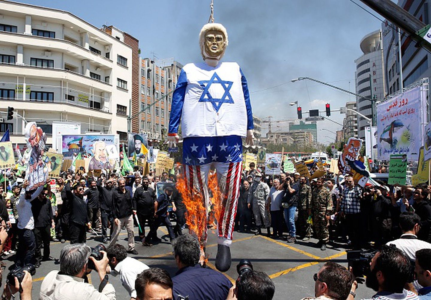 2018年6月8日，伊朗民众在德黑兰某处焚烧身穿美以国旗的时任美国总统特朗普的纸人模型，以抗议后者单方面退出伊核协议的决定。（Getty Images）