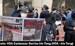 手持香港《苹果日报》的香港市民梁先生在西九法院大楼外排队，他形容防疫限聚令使香港成为一个大监狱，3月1日逾千人排队声援47名被控国安法的民主派人士有如”放监” (美国之音/汤惠芸)