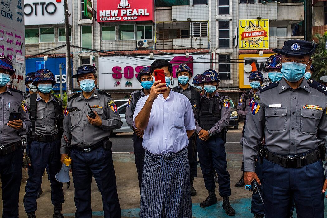 一名便衣警察在仰光拍摄记者和抗议者。