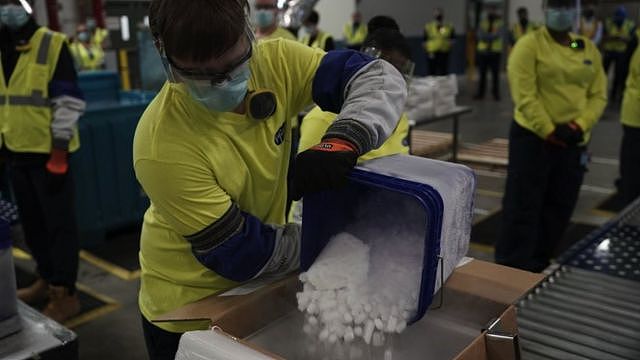 美国辉瑞-BioNTech疫苗全球供应中心的工人向冰桶里倒冰块