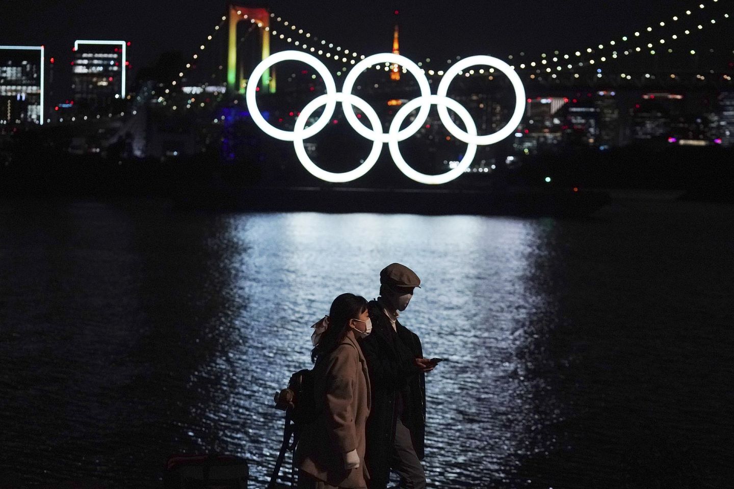 日本民间对于举办东京奥运会缺乏信心。图为2020年12月1日，行人走过位于东京御台场的一处漂浮在水面上的奥运五环标志。（AP）
