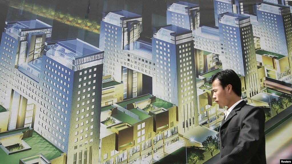 资料照：一名男子走过北京街头张贴的一个新开楼盘的广告牌。