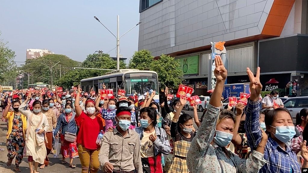 缅甸抗议民众走在仰光街头，并高举象征抗议独裁的三个手指的手势。