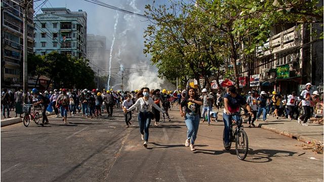 Anti-military coup protesters run in the middle of tear gas smoke during a demonstration to demand the release of State Counsellor of Myanmar, Aung San Suu Kyi on February 01, 2021