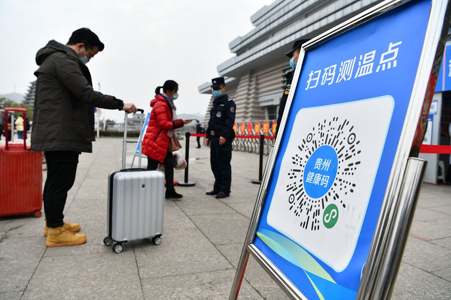 2021年春运第一天，1月28日，贵州省凯里南高铁站铁路派出所的警员在引导乘客用手机扫描健康码进站乘车。（新华社）