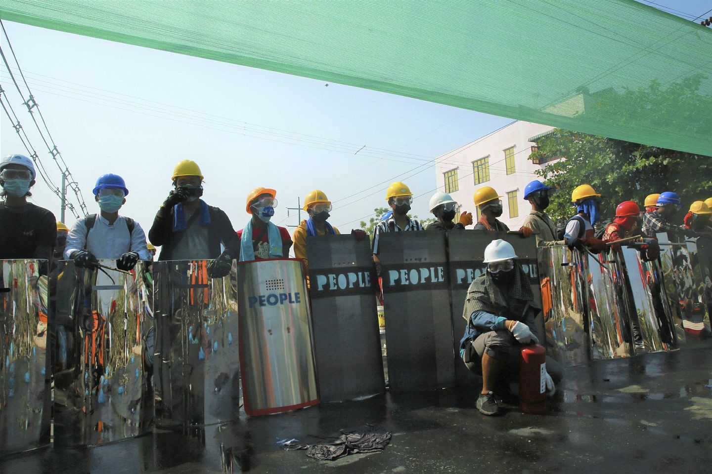 戴着头盔和盾牌的反政变抗议者为警察准备了催泪弹。(AP )