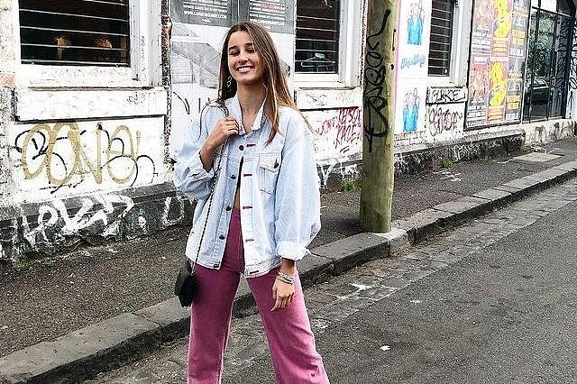 Girl standing on a street in front of a wall with graffiti