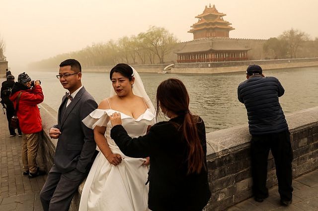尽管有沙尘暴，一对新人在故宫的角楼附近拍摄婚纱照。