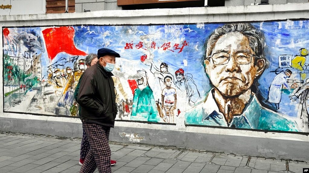 资料照片：在中国中部城市武汉封城76天纪念日前夕，戴着口罩的居民走过一幅名为“记忆”的壁画，武汉是首次发现冠状病毒的地方。(2021年1月22日)