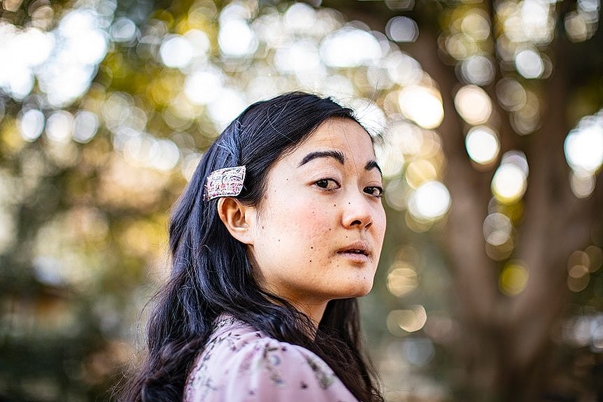 The poet, journalist and novelist Jessie Tu staring at the camera, park in the background