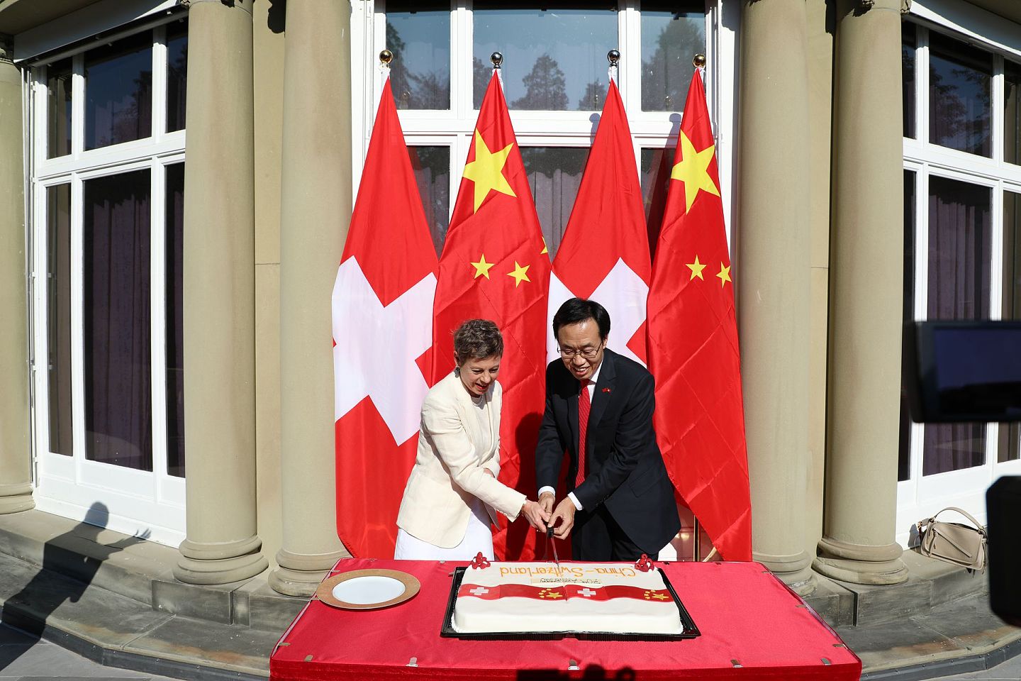 2020年9月15日，中国驻瑞士大使王世廷（右）在使馆举办中瑞建交70周年庆祝活动。图为他与瑞士外交部代理国务秘书马婷（Krystyna Marty）在活动期间共同以切蛋糕互致祝贺。（中国驻瑞士大使馆）
