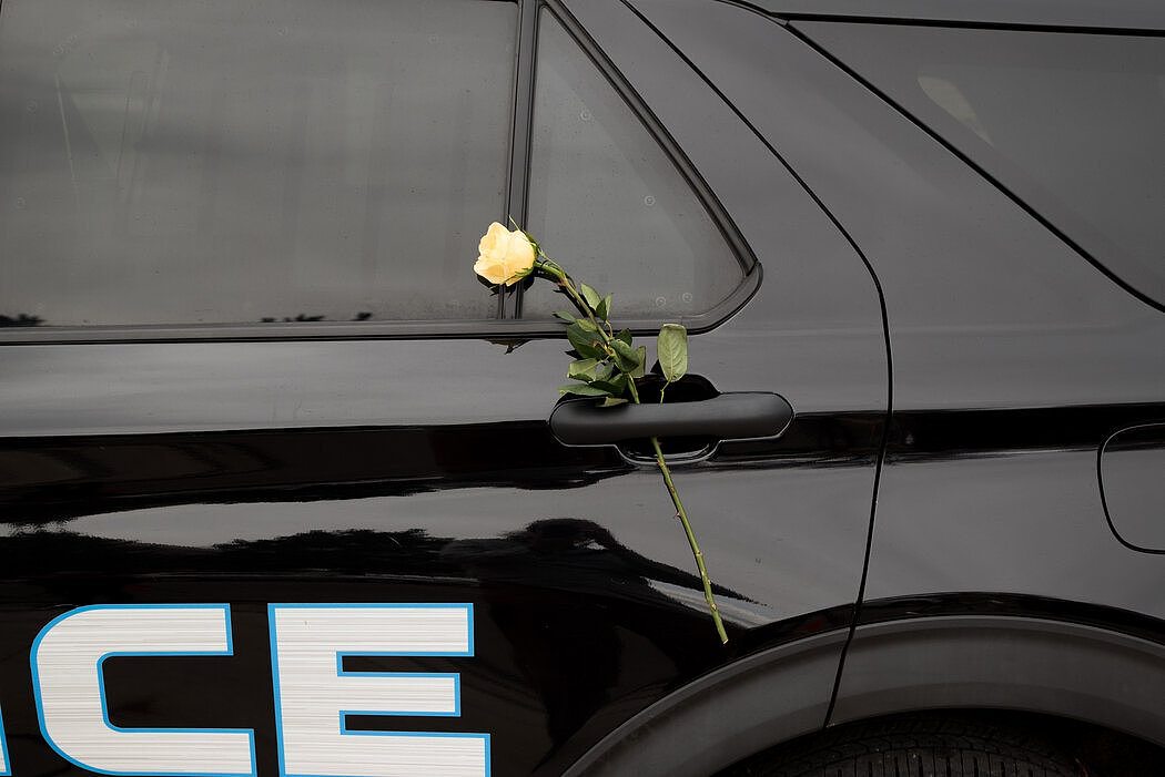 在博尔德警察局的临时纪念仪式上，一辆警车上放着一朵玫瑰。