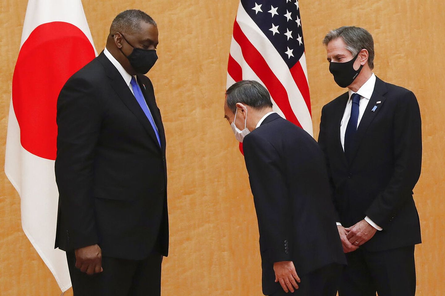 菅义伟（中）向美国防长奥斯汀（左）致意的画面极具冲击性。（美联社）