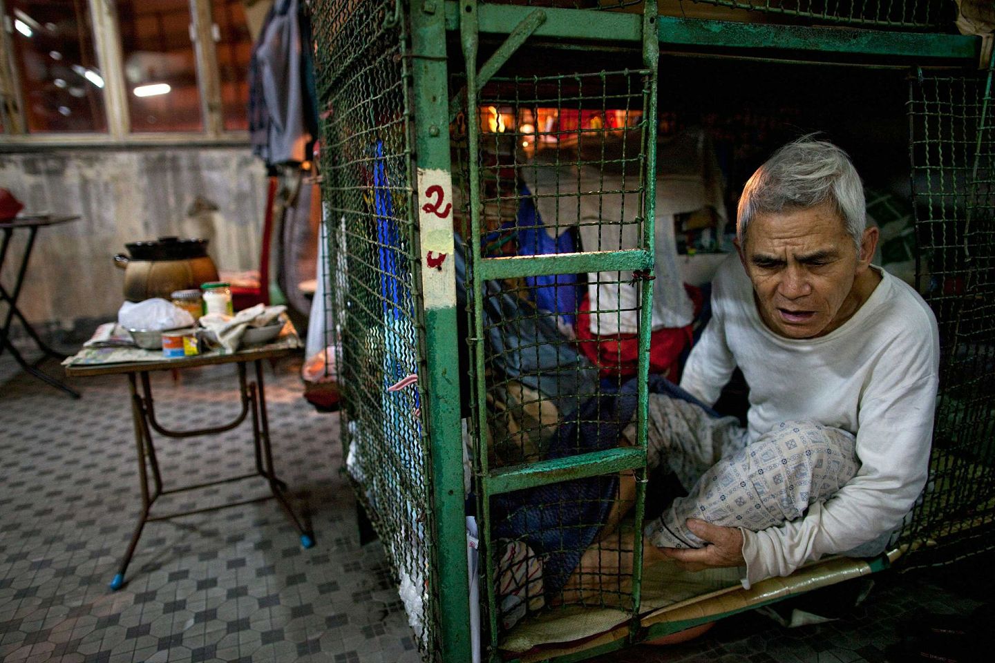 2010年11月27日，香港一位78岁老人坐在他的“笼屋”里。（VCG）