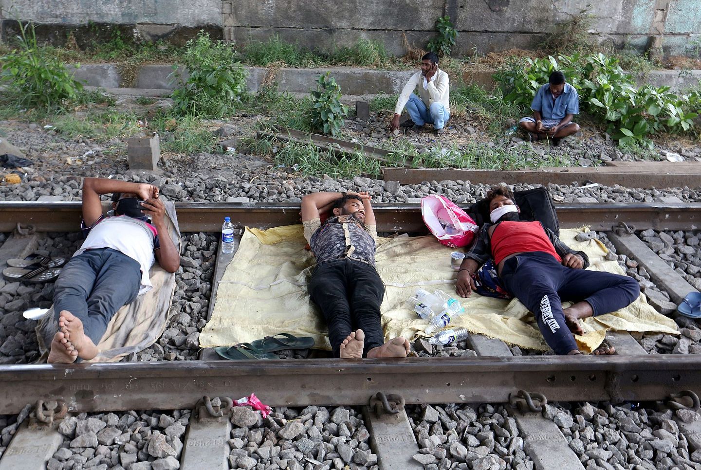 印度孟买，一班工人在火车铁轨附近休息，图为该国正在经历为期21日的全境封城。（Reuters）