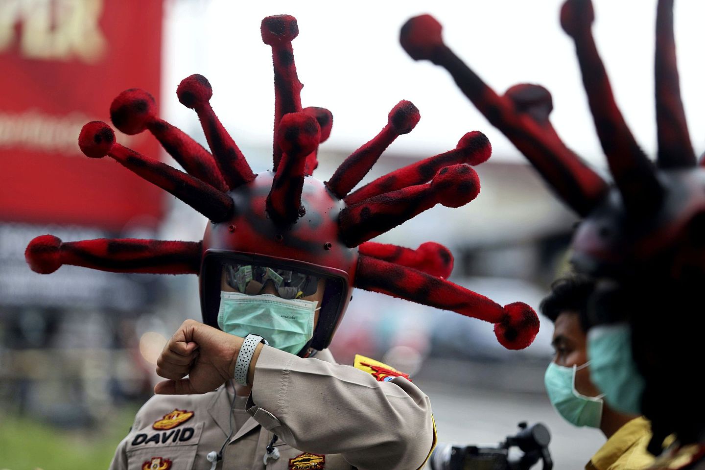 印尼莫佐克托（Mojokerto）街头，有警员执勤时戴上新冠病毒形状的头盔，借此提醒民众防疫。（AP）