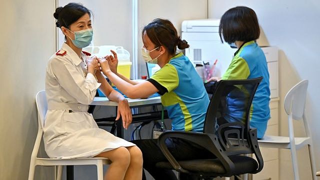 香港某社区疫苗接种中心内一位女护士（左）接受一位女工作人员（右）注射科兴新冠病毒疫苗（23/2/2021）