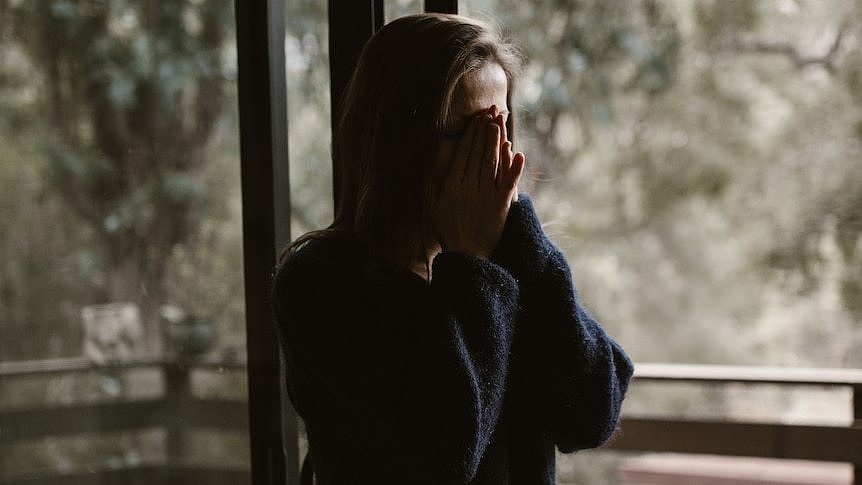 A woman with her hands over her face.